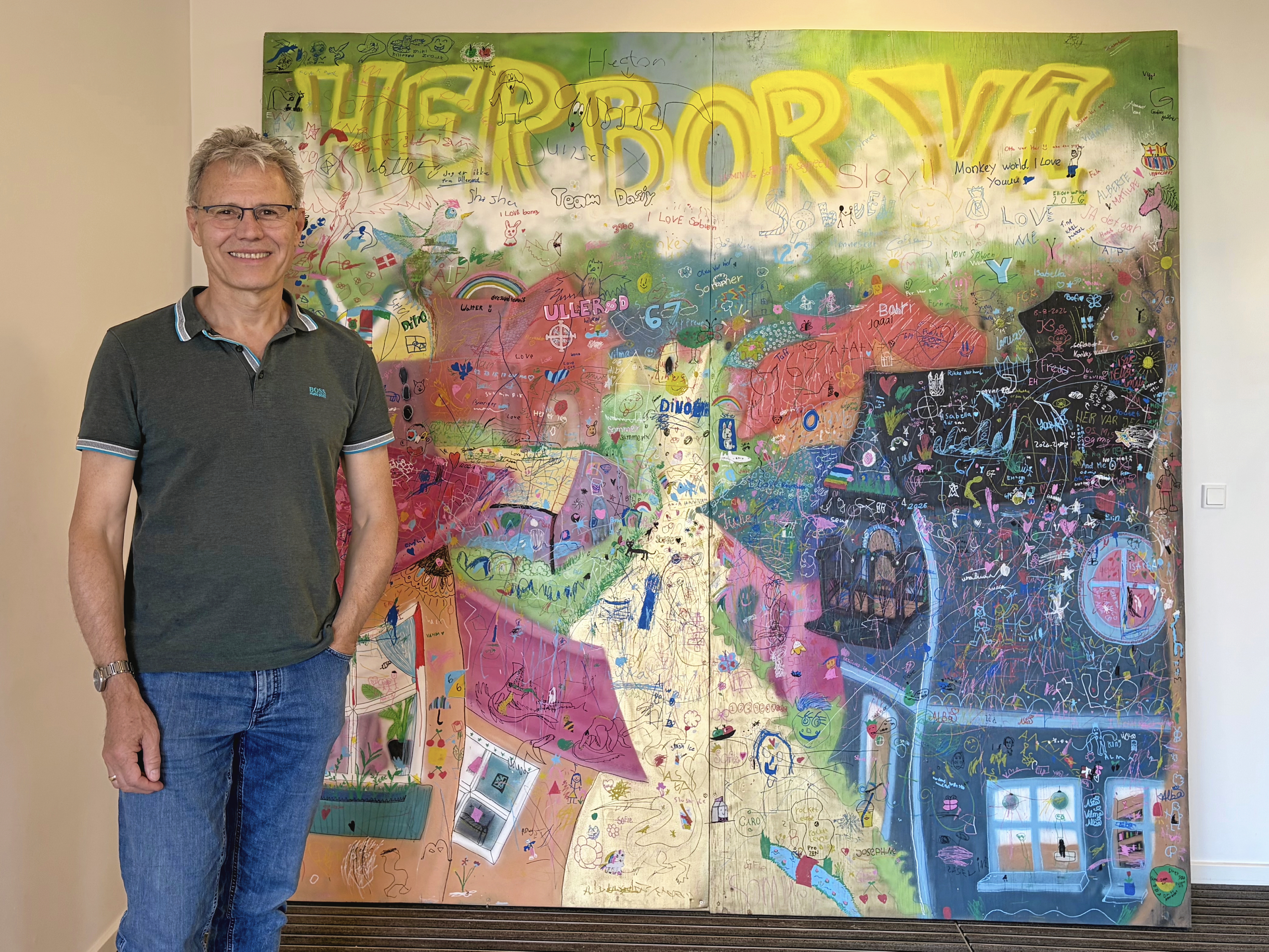 Børn og unge satte deres personlige præg på fællesmaleriet “Her bor vi”, der nu byder alle velkommen ved Ullerød Kirkes sognehus.