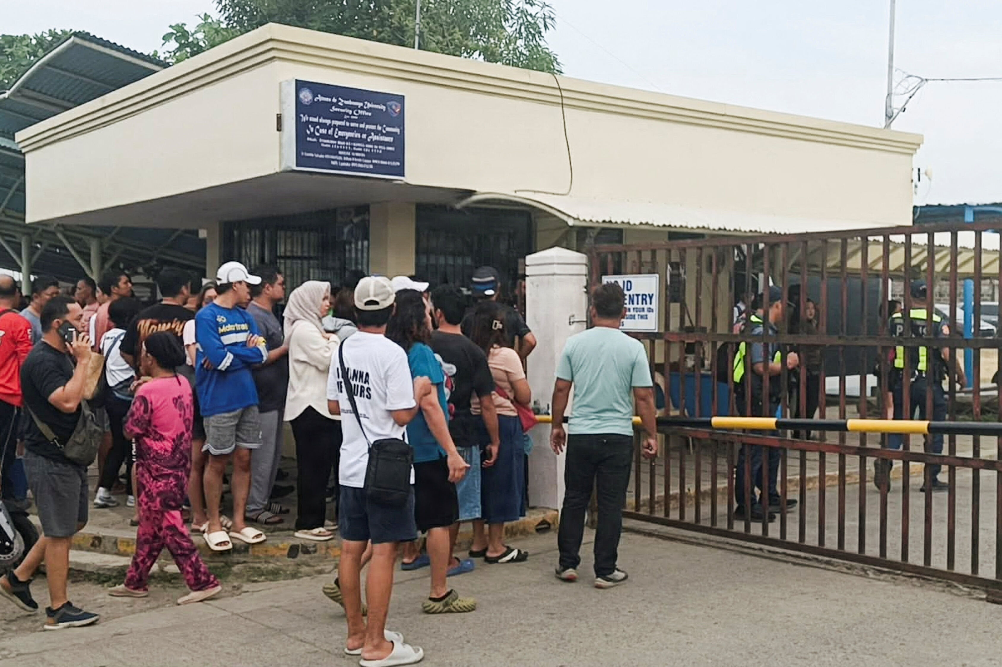 Billede fra tirsdag viser folk uden for Ateneo de Zamboanga University, hvor et skyderi har fundet sted. To elever har mistet livet - blandt andet den formodede gerningsperson.