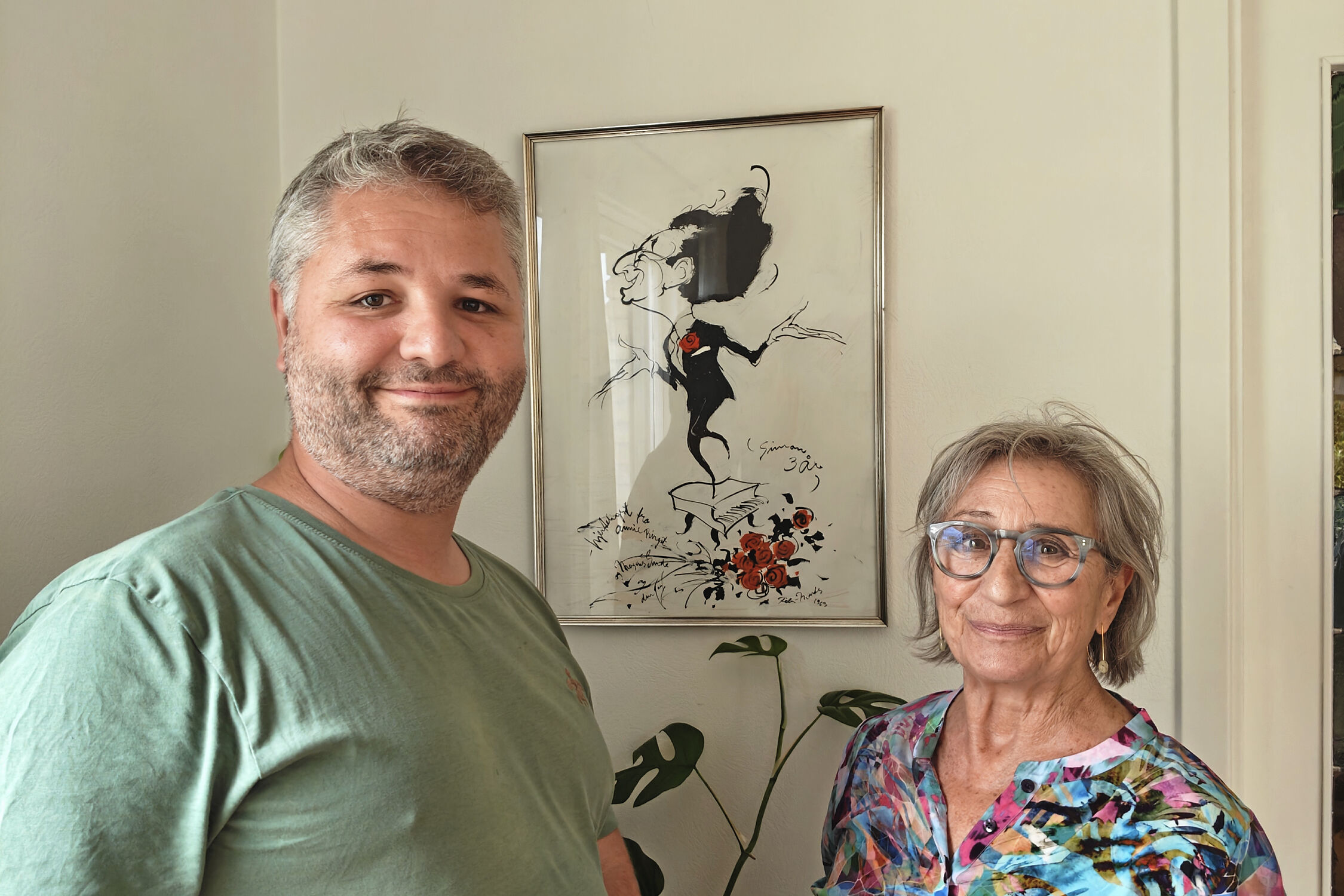 Hannibal og Pia sammen i stuen, hvor en tegning af Simon Rosenbaum fra hans tid som entertainer hænger på væggen.