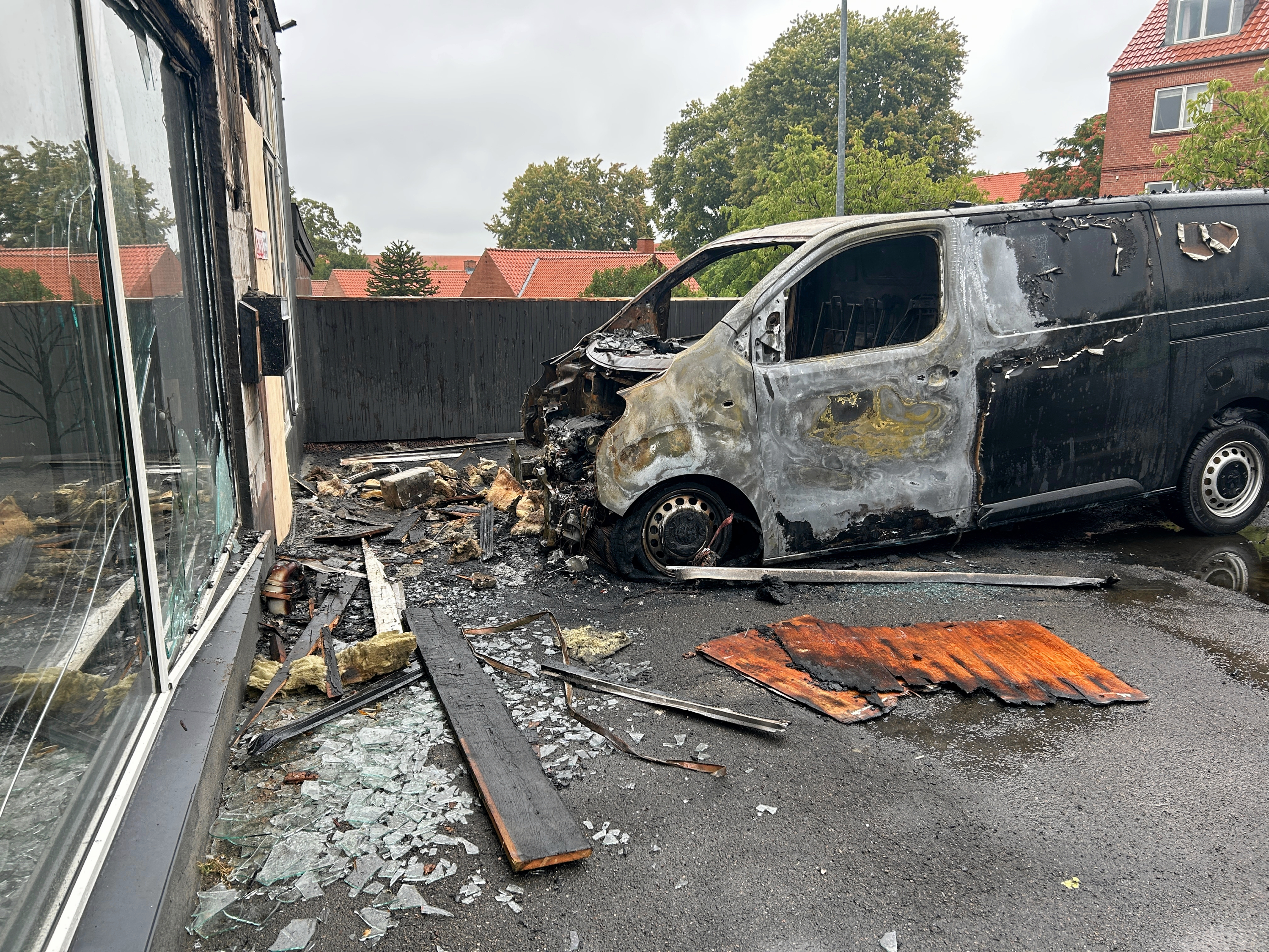 Flammerne spredte sig fra kassevognen og fik også fat på facaden til frisørsalonen Senior Klip. Her ses den udbrændte bil torsdag formiddag.
