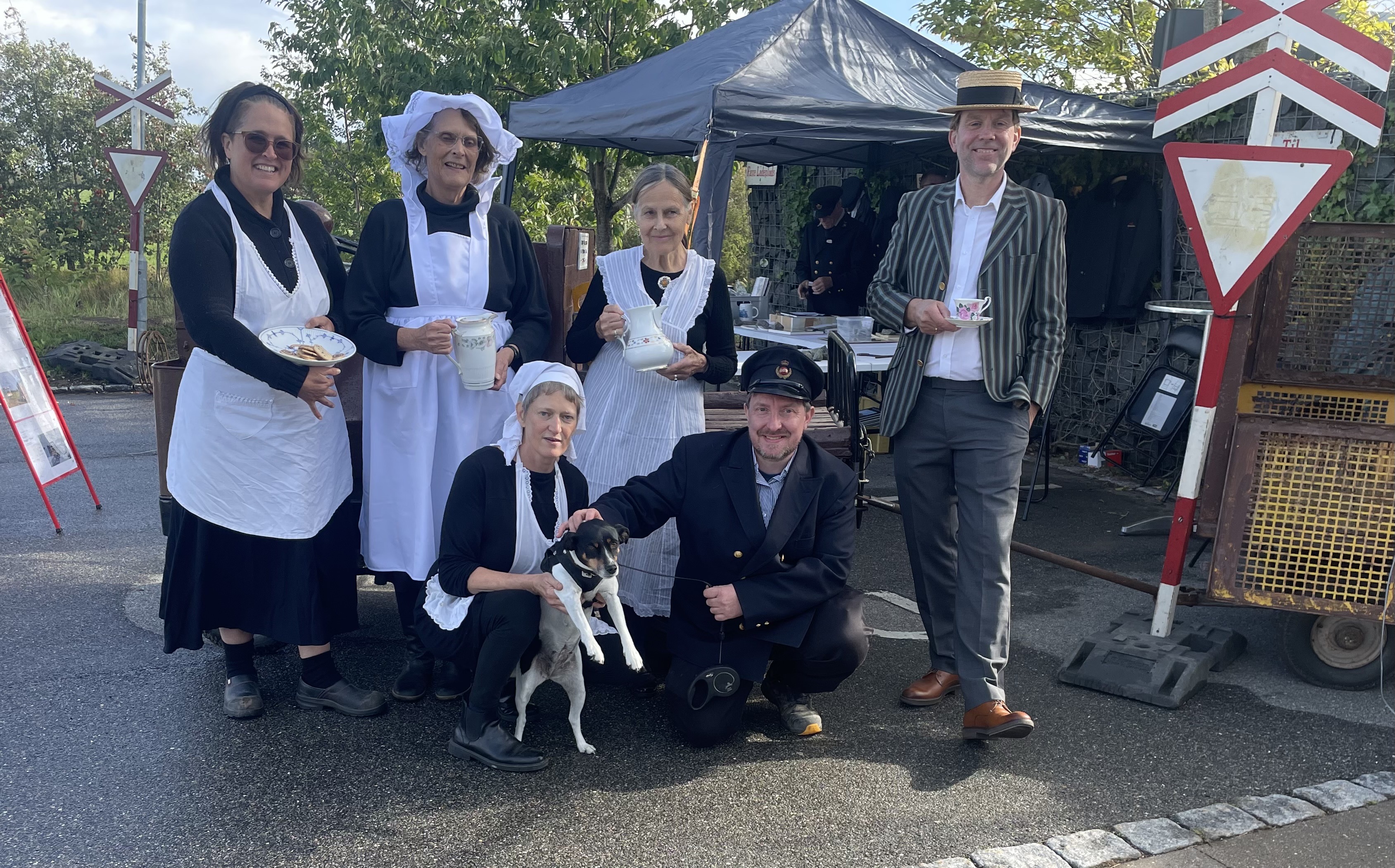 Himlingøje Bylaug fejrer trinbrættets 100 år. Serveringspersonalet Kate Pfeiffer, Lis Hartmand, Anne-Lis Langhoff og Anders Raahauge (formand). Nederst Johanne og hunden Rosa og Henrik Gudmund Jensen fra Jernbaneklubben.