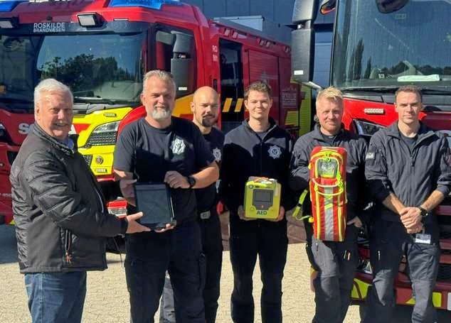 Henrik Schakow, direktør i First AED (tv.) og Roskilde Brandvæsens operative leder, Bo Henrik Jensen med First AED-appen - men det var blandt de menige brandfolk, den brugbare idé blev fostret.