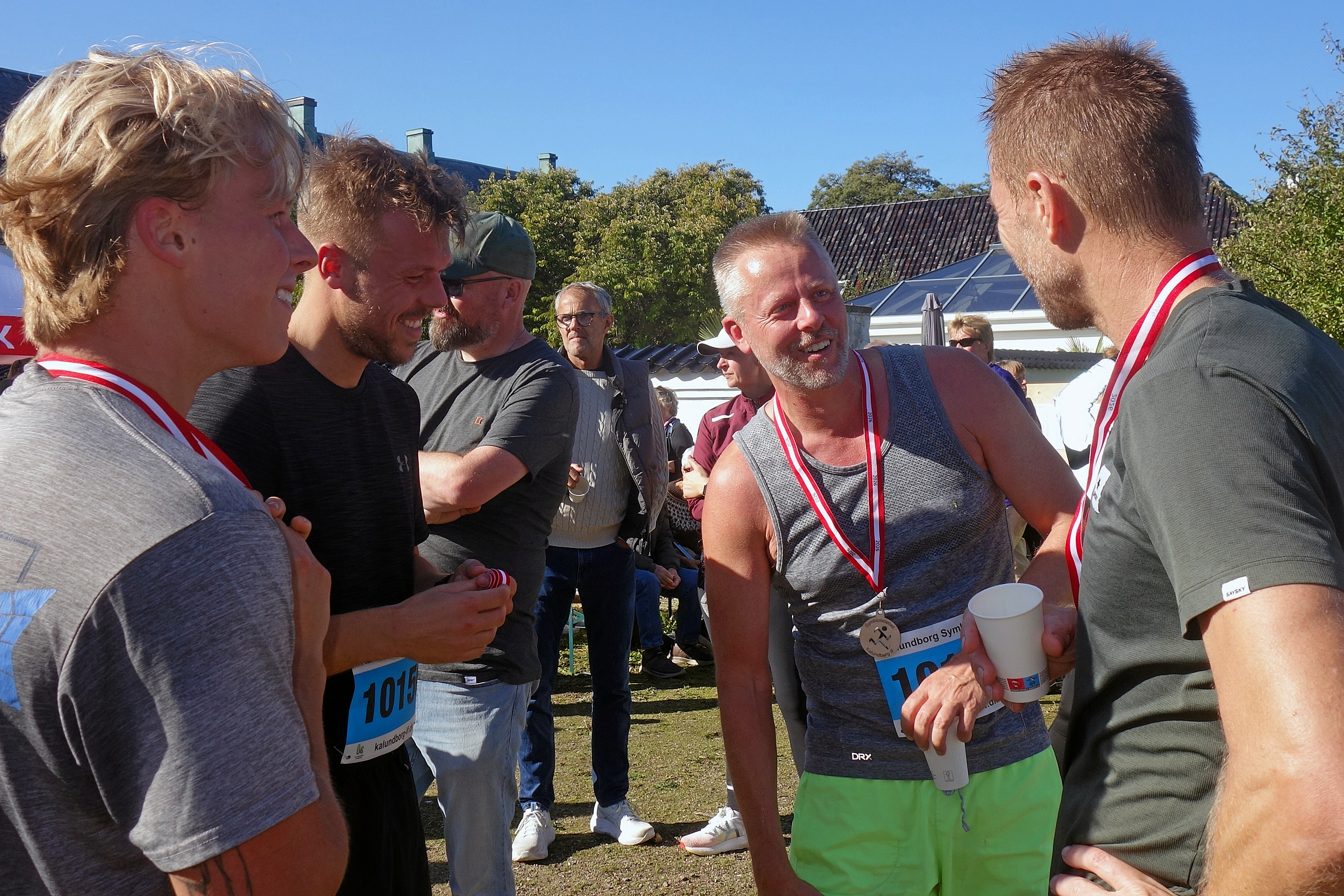 Glade og stolte mænd med deres medaljer hygger sig efter løbet.